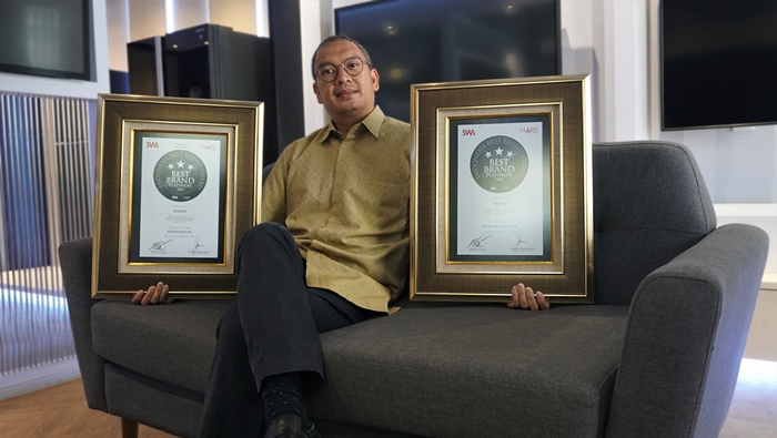 a - Andrew Gultom Selaku Head of HA Product Strategy Division berfoto bersama dua penghargaan Indonesia Best Brand Awards 2020